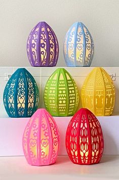 four brightly colored paper lanterns sitting on top of a white counter next to each other