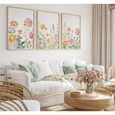 a living room filled with white furniture and paintings on the wall above it's windows