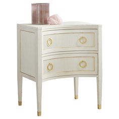 a white dresser with two drawers and a pink candle on it's side table