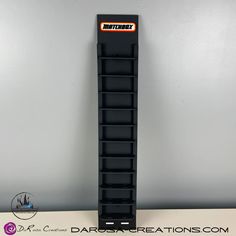 a black storage rack on top of a white table next to a gray wall with the words dartson creations written on it