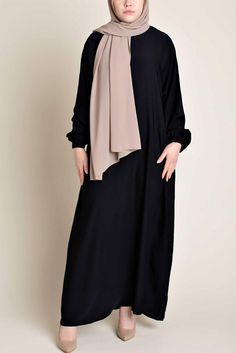 Model wearing a classic Abaya with side pockets in a black color - Front pose - Momina Hijabs Black Long Sleeve Abaya For Fall, Elegant Black Abaya With Modesty Panel, Modest Black Abaya With Long Sleeves, Modest Black Long Sleeve Abaya, Modest Long Sleeve Black Abaya, Black Long Sleeve Hijab For Eid, Black Abaya With Modesty Panel For Eid, Modest Black Thobe For Eid, Black Long Abaya With Modesty Panel