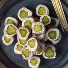 there are many rolls on the plate with green sauce and chopsticks next to it