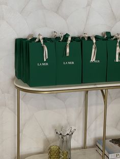 three bags are sitting on top of a table with two vases and some books