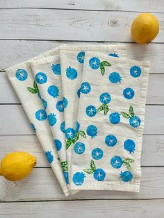 three napkins with blueberries on them next to lemons