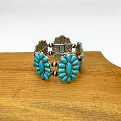 Western Concho Silver Tone Stretchy Bracelet in Turquoise. Pictured sitting on a wood piece with a white background. Western Style Turquoise Bracelet With Concho, Western Turquoise Bracelets With Concho, Adjustable Turquoise Cuff Bracelet With Concho, Adjustable Turquoise Western Bracelet, Western Turquoise Bracelet With Concho, Southwestern Blue Concho Bracelets, Western Turquoise Bangle Cuff Bracelet, Western Style Turquoise Bracelet, Hand Tooled, Vintage Turquoise Cuff Bracelet With Concho