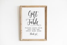 a wooden frame hanging on the wall above a sign that says, gift table please leave your gift for the sweet baby here thank you