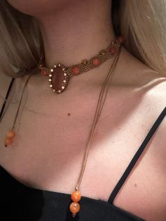 a close up of a woman wearing a necklace with an orange bead on it