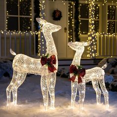 two lighted reindeer statues in front of a house