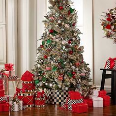 a christmas tree decorated with red, white and black ornaments is surrounded by presents on the floor