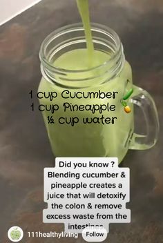 a cup filled with green liquid sitting on top of a counter next to a sign