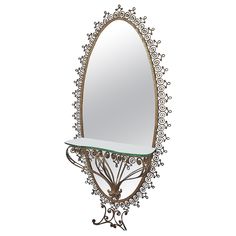 an ornately designed mirror with a glass shelf on it's side, against a white background