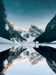 the mountains are covered with snow and reflecting in the water