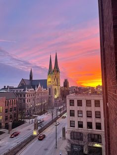 the sun is setting over an old city with tall buildings and steeples in the background