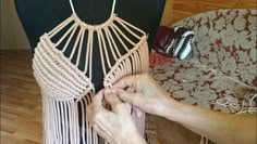 a woman is working on a piece of art that looks like a crochet dress