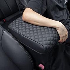 a man sitting in the back seat of a car with his hand on the armrest