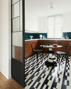 a kitchen with black and white checkered flooring, two chairs at the table