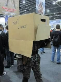 a man with a cardboard box on his head is standing in the middle of a crowd