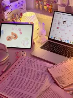 two laptops sitting on top of a desk next to papers and pens with bunny ears on them