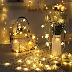 some lights that are sitting on a table next to a purse and vase with flowers in it