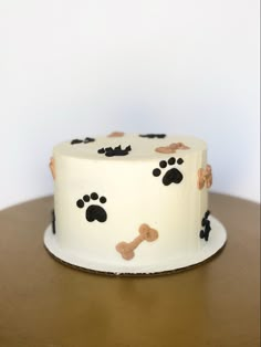 a white cake with black and brown paw prints on it's side sitting on a wooden table