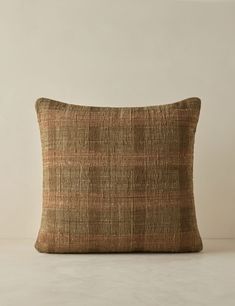 a brown and tan pillow sitting on top of a white floor next to a wall