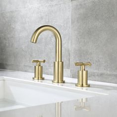 a gold faucet on a white sink in a bathroom