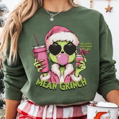 a woman wearing a green christmas sweater holding a pink drink