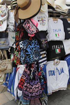 a pile of t - shirts and hats are stacked on top of each other at a market