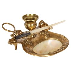 a gold plate with scissors and a bowl on it's side, next to a candle holder