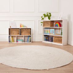 a white rug in the middle of a room with bookshelves and baskets on it