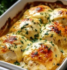 a casserole dish with chicken and cheese covered in parmesan sauce, garnished with fresh herbs