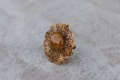 This round brooch in an ornate gold tone frame is perfect for brides or bridesmaids. It measures 1 3/4 in diameter and the clasp closes securely. The brooch/pin is vintage and can compliment any outfit. It can be used for jacket, dress, scarf, wedding jewelry or hat pin. To view my complete Brooch Collection, visit: https://www.etsy.com/shop/AleksJewelry?ref=hdr_shop_menu&section_id=18825972 Search for my entire Shop Collection visit: https://www.etsy.com/shop/AleksJewelry Vintage Brass Wedding Brooches, Victorian Gold Brooch For Wedding, Victorian Gold Wedding Brooch, Gold Brooches With Intricate Design For Wedding, Brass Brooch For Wedding, Brass Brooch Jewelry For Wedding, Antique Gold Brooches For Wedding, Brass Wedding Brooch, Gold Filigree Brooches For Wedding