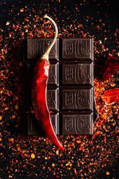 chocolate bar with chili pepper on top and spices around it, surrounded by red peppers