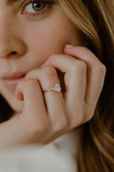 a close up of a person with a ring on their finger and her hand near her face