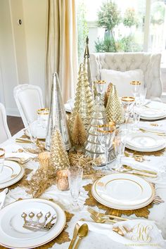 a dining room table set for christmas with gold and silver decorations on the place settings