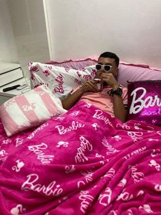 a man laying in bed under a pink blanket