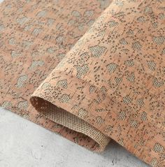 an orange and beige patterned rug on top of a cement floor with a white wall in the background