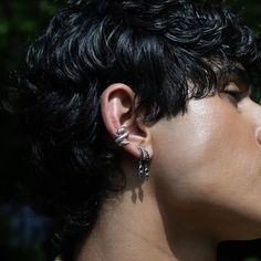 a close up of a person with black hair and ear piercings on their ears