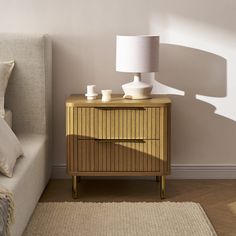 a nightstand with two vases on it next to a couch