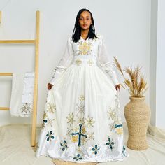 This stunning neutral-colored Habesha dress combines the subtle elegance of beige and grey tones with intricate beadwork that exudes sophistication. Designed with delicate hand-beaded details along the neckline and sleeves, this Ethiopian traditional dress is perfect for those who appreciate understated elegance. The soft, flowing fabric makes it ideal for both everyday wear and special occasions.  Key Features: Cultural Heritage: Adorned with exquisite handwoven details that honor Ethiopia's rich traditions. Flattering Design: The flowing silhouette ensures you look stunning at weddings, festivals, or any event where you want to shine. Ethical Craftsmanship: Handmade by skilled Ethiopian artisans, embracing tradition while making a bold fashion statement. Care Instructions: For best resul White Pearl Embroidery Kaftan, Anarkali Style Embroidered Off White Dress, Floor-length Pearl Embroidered Dress For Eid, Floor-length Pearl Embroidery Dress For Eid, Floor-length Dresses With Pearl Embroidery For Eid, White Embroidered Dress With Pearl Details, Cream Floor-length Dress With Intricate Embroidery, Floor-length Cream Dress With Intricate Embroidery, Traditional Maxi Dress With Pearl Embroidery