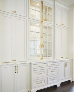 a kitchen with white cabinets and gold trimmings on the glass front cabinet doors