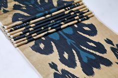 six pencils sitting on top of a blue and beige patterned cloth with black designs