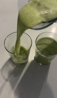 a pitcher pouring green liquid into two glasses