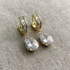 "These Heatherly Designs earrings are a modern take on bridal or if you like your bling, perfect for everyday. They feature huggie hoops paved with square princess cut CZ, which CZ pears are set in simple prong settings and dangle beneath. These earrings are solid jewelers brass plated in 14k. ●Nickel free ●Size: 1 1/2\" x 3/8\" or 3.81 x 1cm ●Hoop Width: 1/8\" or .32cm ●Arrives in our signature Heatherly gift box. Handmade with ❤ by Heather ● ● ● ● ● ● ● ● ● ● ● ● ● ● ● ● ● ● ● ● ● ● ● ● ● ● ● Gold Teardrop Huggie Earrings In Cubic Zirconia, Gold Teardrop Huggie Earrings With Cubic Zirconia, Gold Teardrop Earrings With Prong Setting, Gold Pear-shaped Bridal Earrings With Prong Setting, Gold Teardrop Diamond Earrings For Gift, Gold Cubic Zirconia Teardrop Earrings As Gift, Gold Drop Earrings With Prong Setting, Prong Setting Drop Huggie Earrings For Wedding, Classic Gold Teardrop Cubic Zirconia Earrings