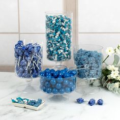 blue and white candies in glass containers on a table with flowers, candles and vases