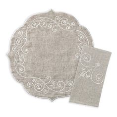 two placemats and a napkin on top of each other, one with an embroidered design