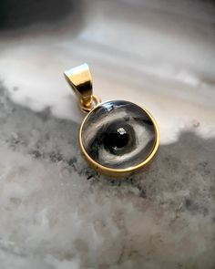 Lover's Eye pendant with an oil painting encased in gold plate over sterling with a quartz crystal cabochon which gives a magical magnifying effect, measuring 1/2" in diameter; 18" 16k gold over brass chain included. THE HISTORY: Lover's Eyes were a jewelry trend c.1785-1830 of brooches set with tiny watercolor portraits on ivory. Since they were cropped to eyes, they were in many ways more direct and intimate than traditional miniature portraits; but also because they were just eyes, they were Brass Cabochon Round Pendant Necklace, Mystical Gold Jewelry For Anniversary, Gold Mystical Jewelry For Anniversary, Mystical Yellow Gold Jewelry For Gift, Gold Keepsake Jewelry With Large Pendant, Mystical 14k Gold Jewelry Gift, Bronze Cabochon Round Pendant Jewelry, Mystical Engraved Gold Jewelry, Mystical Gold Round Pendant Jewelry