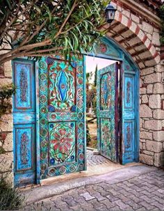 an ornately painted wooden door is open to the outside area with brick walls and cobblestone flooring