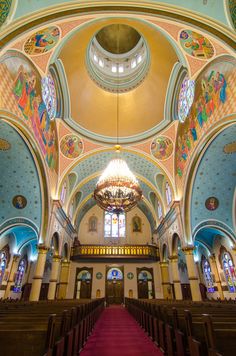 the inside of a large church with stained glass windows and red carpeted pews