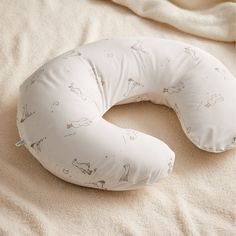 a white pillow on top of a bed next to a comforter and pillows in the shape of animals